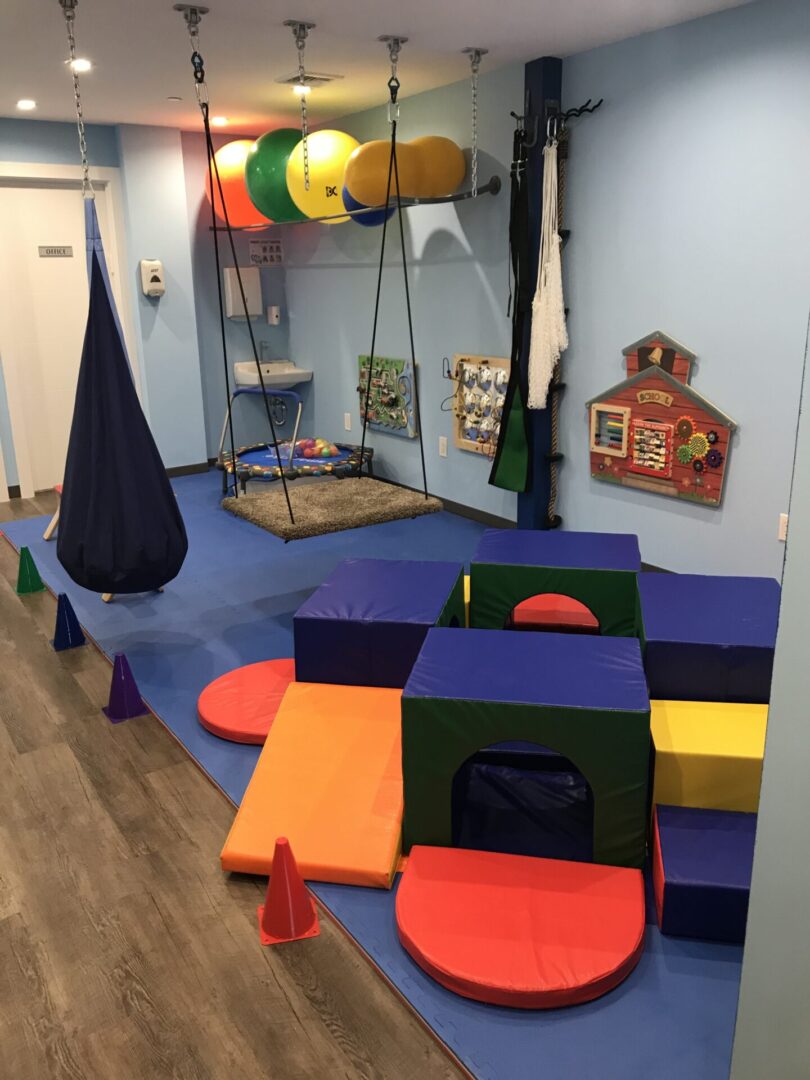 A room with several different colored soft play equipment.