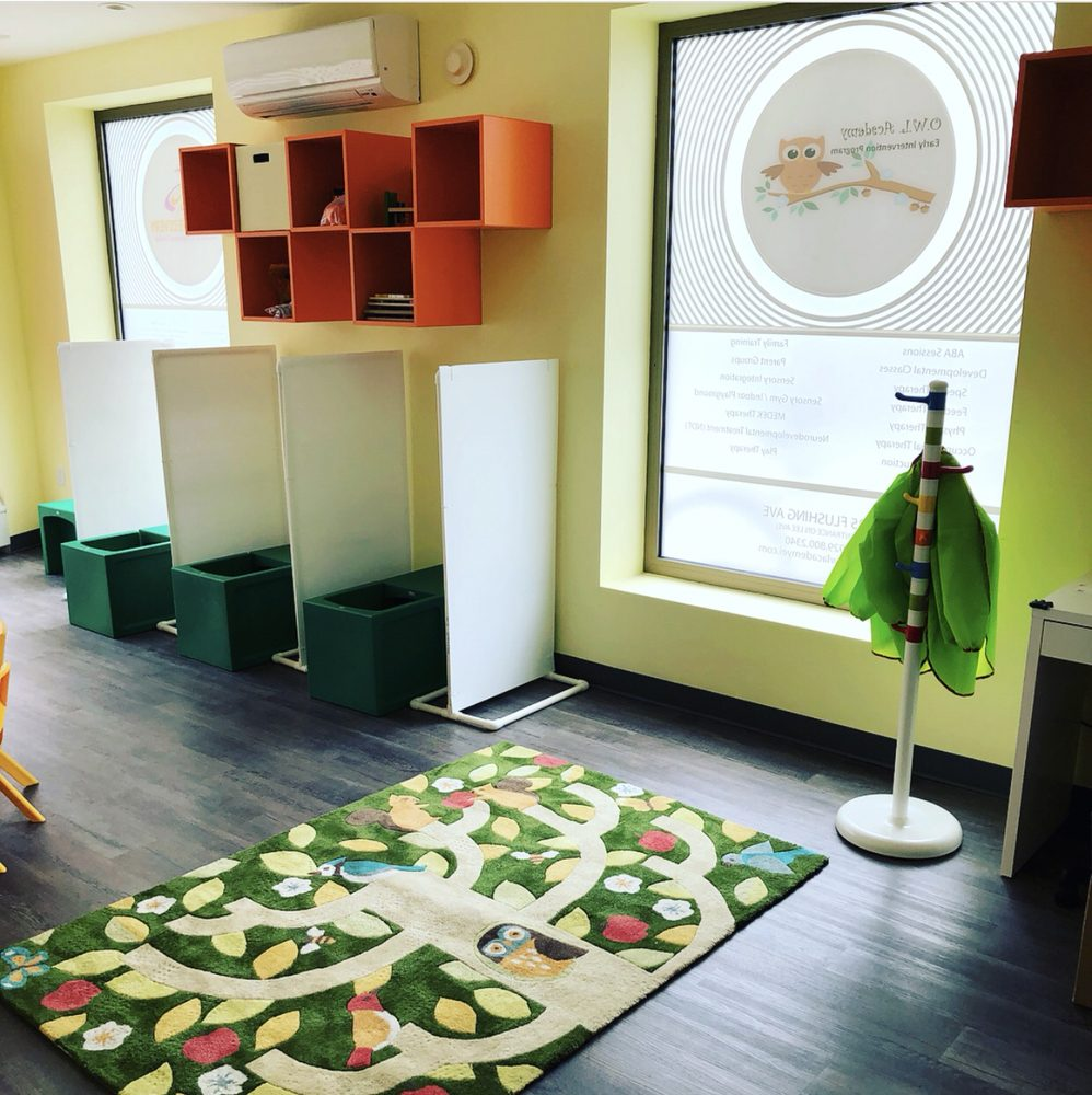 A room with a tree rug and green shelves.