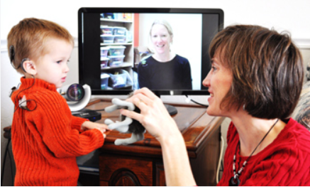 A woman and child playing video games in front of a computer.