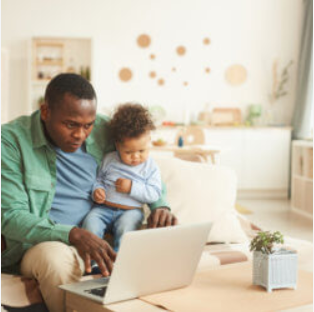 A man and child sitting on the floor using a laptop.