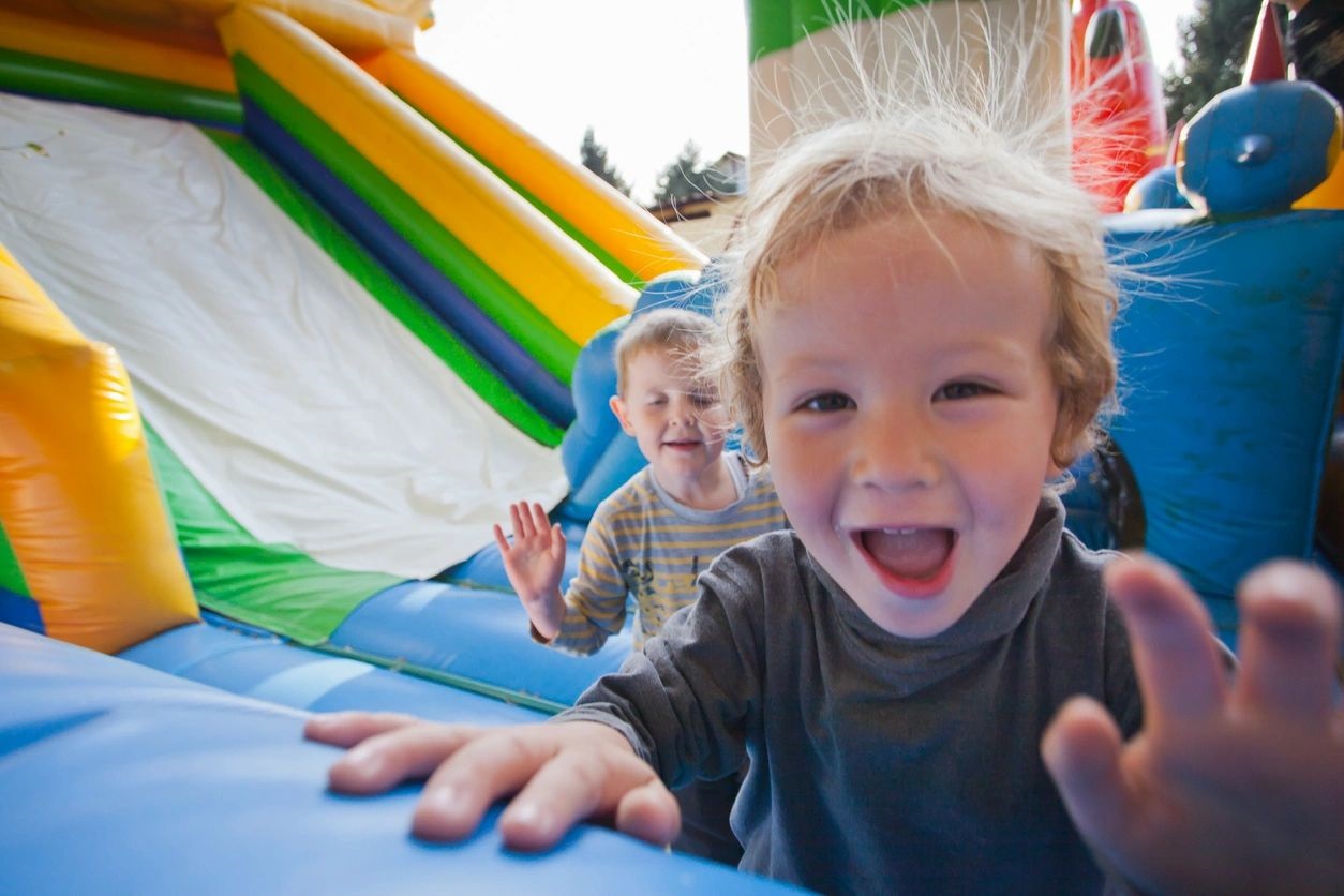 Two children are playing on a bouncy house.