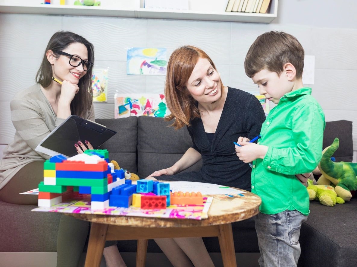 A woman and two children playing with blocks.