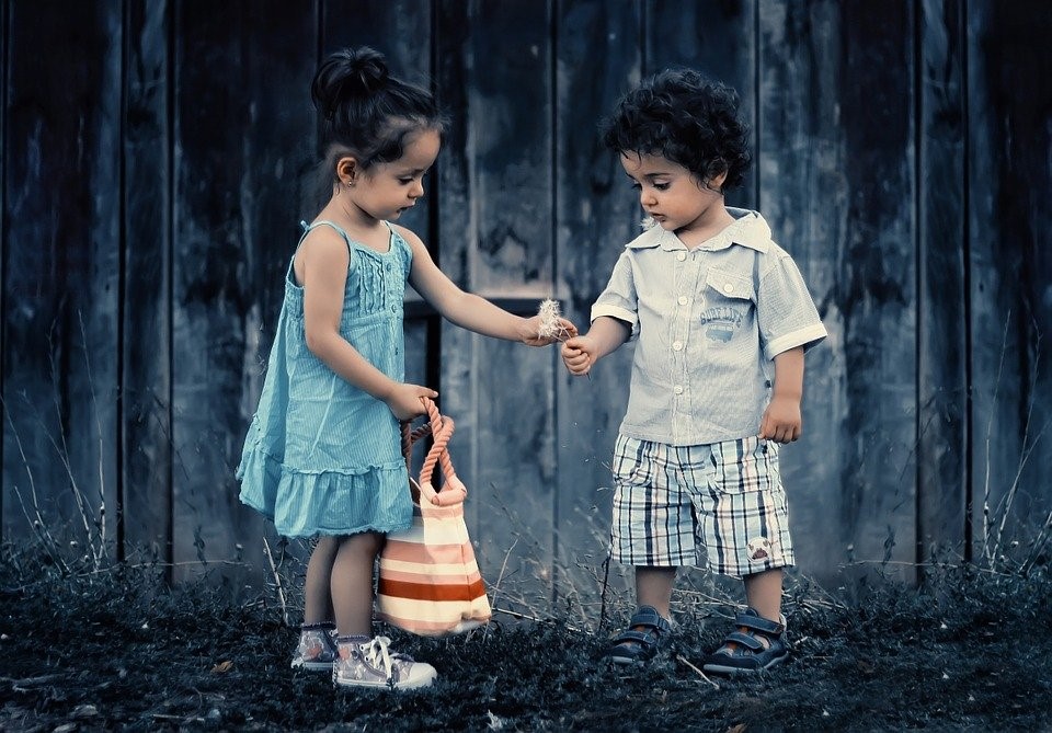 A boy and girl holding hands in front of a fence.