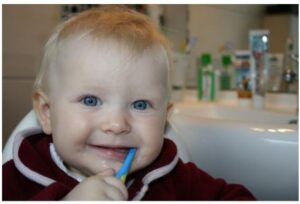 A young child is brushing his teeth with a blue toothbrush.